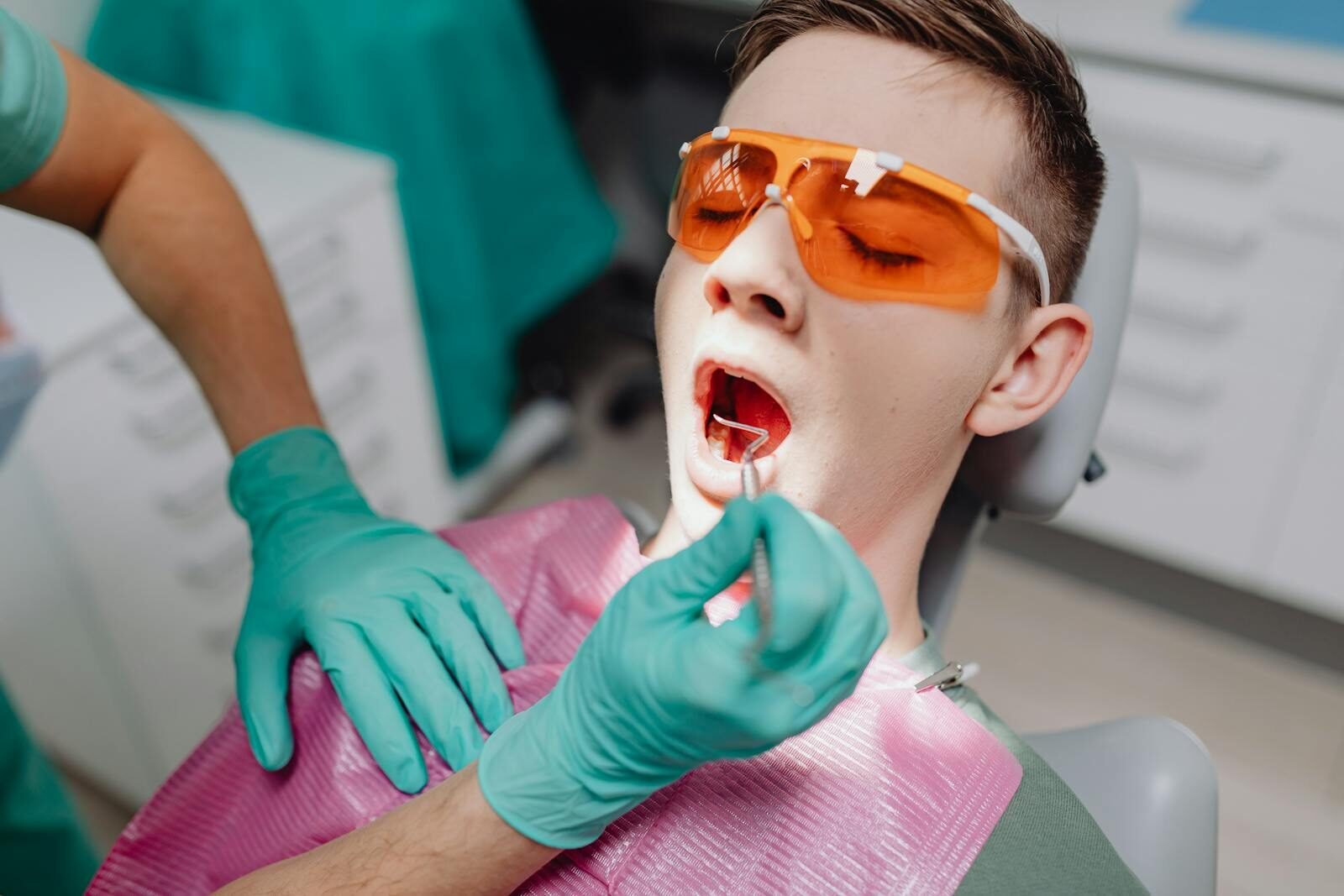A patient receiving dental care while wearing protective eyewear in a clinic setting.